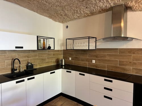 Cuisine moderne à la Maison Melrose Vouvray : armoires blanches, crédence imitation bois, plan de travail noir et acier inoxydable