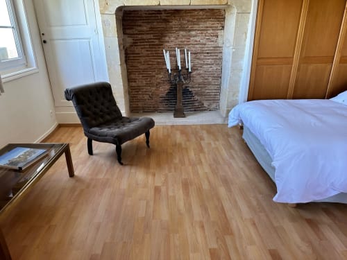 Chambre spacieuse à la Maison Melrose avec cheminée, fauteuil noir et parquet à Vouvray
