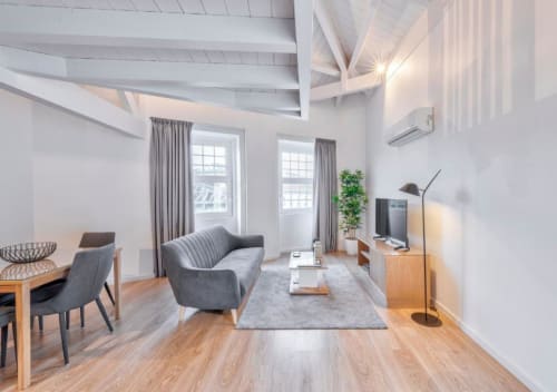 Sala de estar estilo loft moderno no Oporto Comfort Dom Hugo com sofá cinzento, piso de madeira, vigas aparentes e vista para a cidade