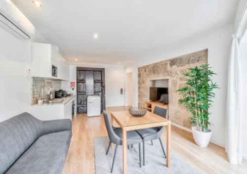 Estúdio moderno no Oporto Comfort Dom Hugo com mesa de jantar, sofá, kitchenete e sala de estar com parede de pedra