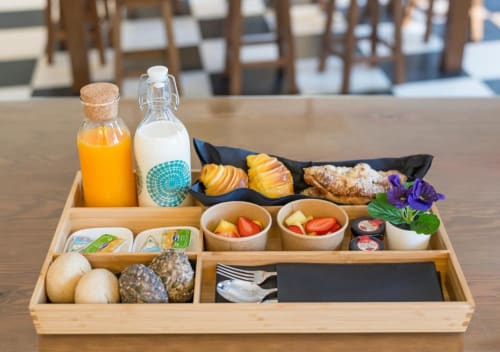 Bandeja de café da manhã no Oporto Comfort Dom Hugo com sucos, leite, pastéis, frutas, pão e flores