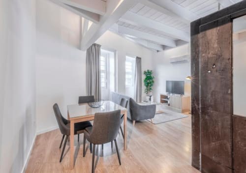 Apartamento em plano aberto moderno no Oporto Comfort Dom Hugo com mesa de jantar, sala de estar, TV e porta de madeira rústica