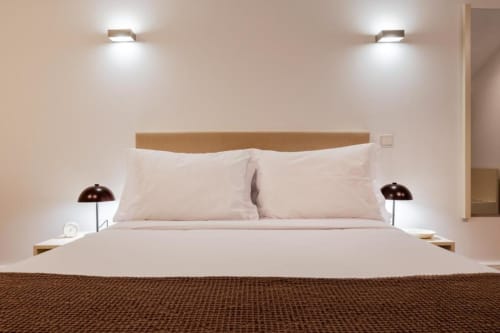Quarto moderno com roupa de cama branca, cabeceira de madeira e iluminação ambiente na Oporto Comfort Charming House no Porto