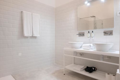 Banheiro moderno com dois lavatórios brancos suspensos, espelho amplo e duche aberto na Oporto Comfort Charming House, Porto