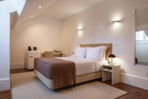 Quarto com vista para o jardim no Oporto Comfort Charming House Porto, com cama, criado-mudo, iluminação moderna e assoalho em madeira.