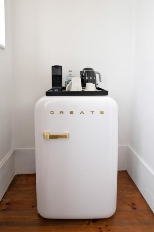 Mini frigorífico CREATE branco com puxador dourado e bar de café no topo, em quarto de hospedaria no Porto
