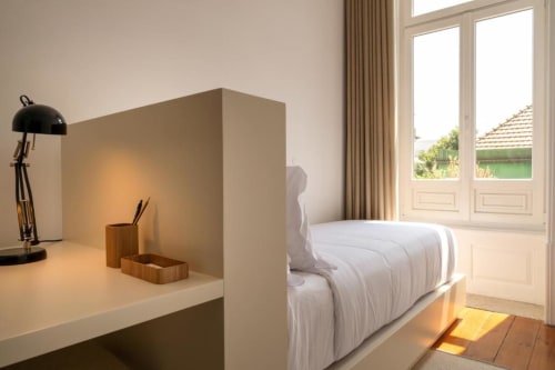 Quarto moderno na Oporto Comfort Charming House com escrivaninha, luminária preta, roupa de cama branca, piso de madeira e vista da cidade