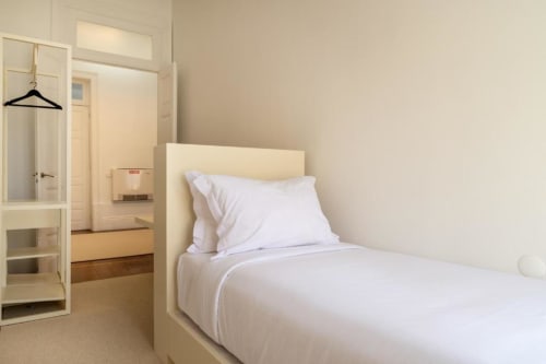 Quarto luminoso na Oporto Comfort Charming House com roupa de cama branca, piso de madeira e vistas da cidade no Porto, Portugal