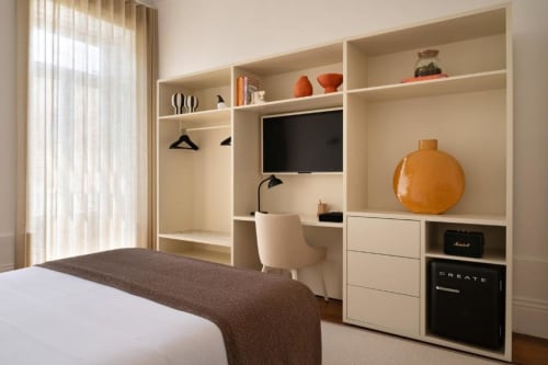 Suite moderna no hotel Porto com prateleiras embutidas, área de trabalho, TV de tela plana e décor contemporâneo com tons quentes