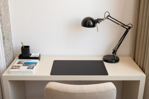 Espaço de trabalho moderno na Oporto Comfort Charming House com escrivaninha branca, luminária preta e vista para o jardim da pensão no Porto