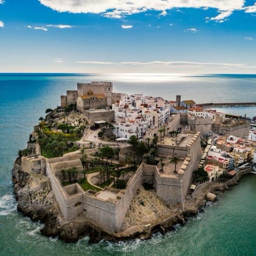Medieval walled town of Peñíscola perched on rocky peninsula surrounded by turquoise Mediterranean Sea