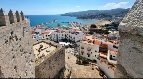 Medieval castle overlooks Peñíscola beach town with turquoise Mediterranean Sea, white buildings, and coastal landscape