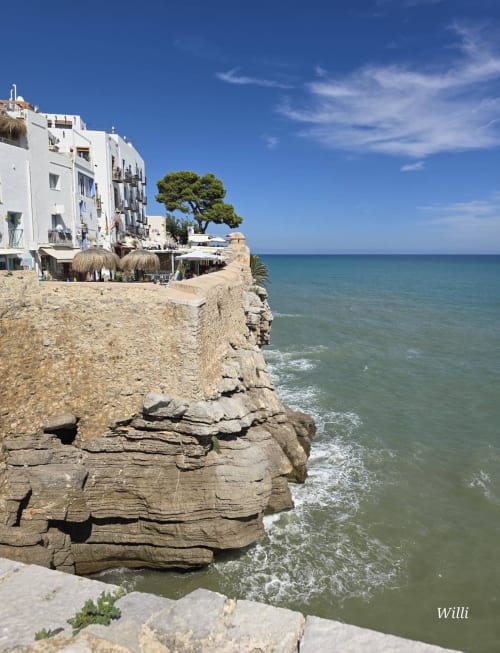 Clifftop apartment building in Peñíscola with Mediterranean Sea views, white architecture, and pine tree overlooking rocky
