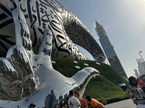 Modern white sculpture with Arabic calligraphy at RentalaYa!, Dubai, with Big Ben visible in background