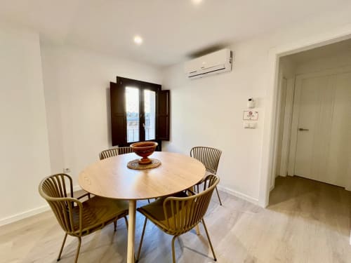 Comedor moderno en apartamento Architettura Apartamentos Úbeda con mesa redonda de madera, sillas contemporáneas y balcón
