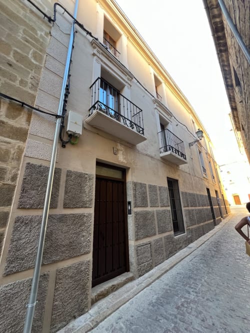 Edificio histórico de piedra en Úbeda, Jaén con balcones de hierro forjado y puertas de madera