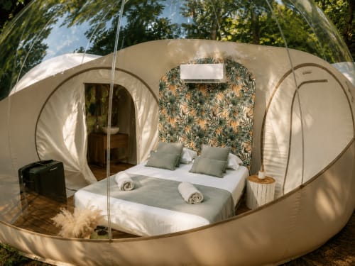 Chambre luxueuse en bulle à La Biche Au Bois avec lit double, vue sur le jardin et tête de lit fleurie à Moncléra