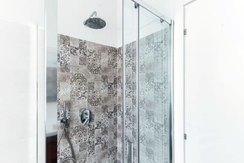 Moderna cabina doccia con piastrelle decorative a motivi presso Lago Suites Como, con soffione pioggia e porte in vetro