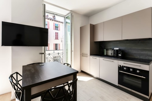 Cucina moderna e zona living della camera 101 Lago Suites Como con vista città, TV schermo piatto e arredi contemporanei