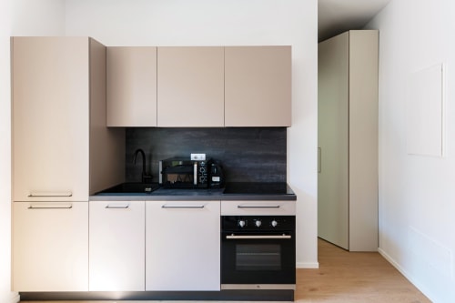 Cucina moderna nella Suite 101 di Lago Suites Como con mobili bianchi, piano di lavoro nero e elettrodomestici integrati