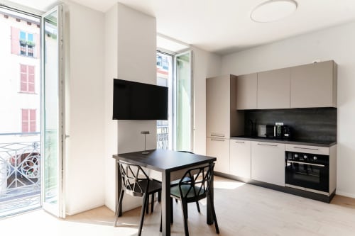 Cucina moderna e zona pranzo nella Suite Lago Como Room 101 con vista sulla città, TV a schermo piatto, tavolo nero e acciaio inossidabile