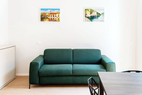 Divano verde moderno nella suite 101 di Lago Suites Como con opera d'arte costiera italiana sopra