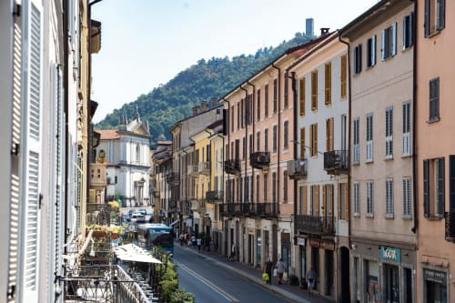 Vista storica della via di Como da Lago Suites: edifici colorati, montagne e architettura cittadina