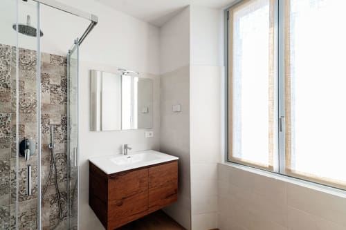 Elegante bagno del Lago Suites Como con vanity in legno, lavabo bianco, box doccia con piastrelle decorate e ampia finestra