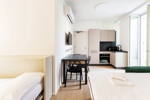 Studio moderno a Lago Suites Como con letto, cucina, tavolo da pranzo e vista sulla città dalla camera 102