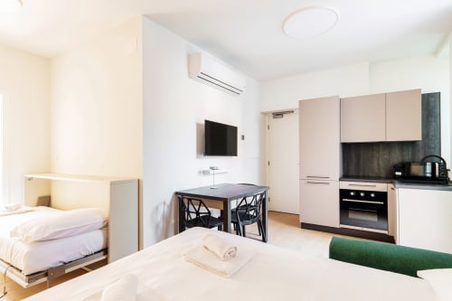 Moderna suite presso Lago Suites Como con letto, angolo cottura, scrivania, TV a muro e climatizzazione
