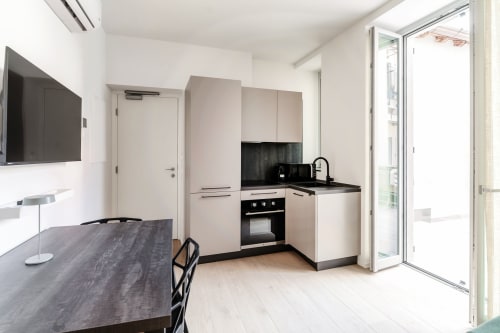 Cucina moderna con elettrodomestici neri e mobili bianchi a Lago Suites Como, con vista sulla città e accesso TV