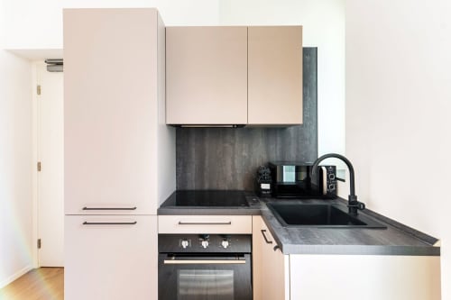 Cucina moderna nella Camera 102 del Lago Suites, Como con mobili chiari, piano di lavoro scuro e elettrodomestici