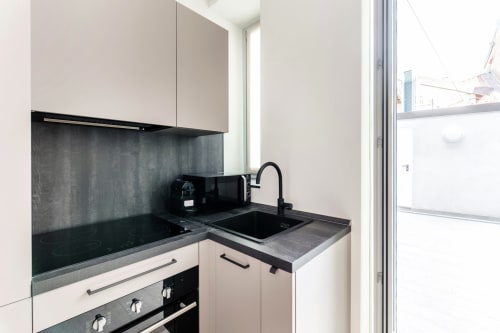 Moderna cucinetta presso Lago Suites Como con mobili bianchi, piano cottura scuro, fornello e lavello nero