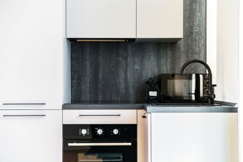 Moderna cucina nella camera 102 di Lago Suites Como con schienale scuro, elettrodomestici in acciaio inossidabile e mobiletto bianco