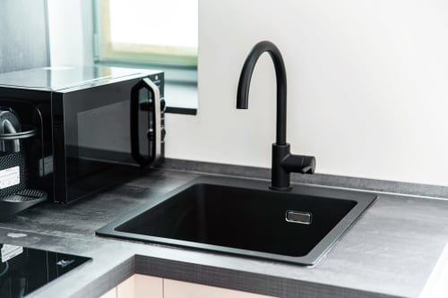 Moderno lavello da cucina nero e rubinetto nella Stanza 102 di Lago Suites Como con microonde e vista sulla città