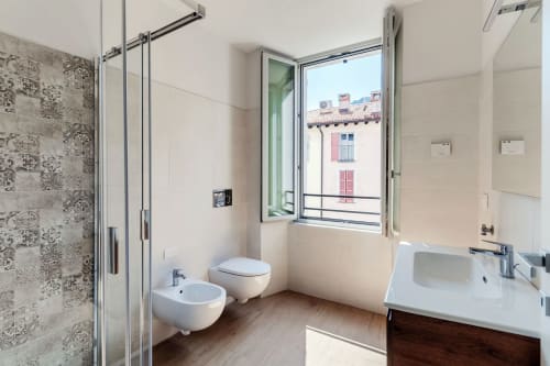 Bagno moderno delle Lago Suites Como con doccia, bidet, wc e finestra con vista sulla città e l'architettura italiana