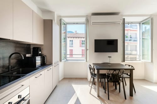 Zona cucina e pranzo moderna di Lago Suites Como con vista sulla città, piani di lavoro neri e arredi contemporanei