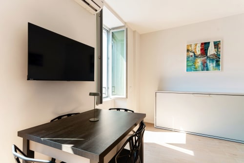 Sala riunioni moderna presso Lago Suites Como con TV a parete, tavolo scuro, lavagna e opera d'arte con veliero