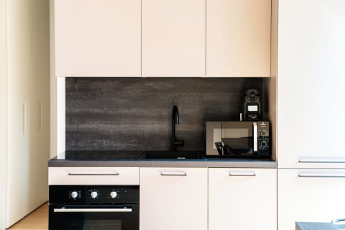 Moderno angolo cottura nella camera 201 di Lago Suites Como con rivestimento scuro, mobili bianchi, forno nero e elettrodomestici