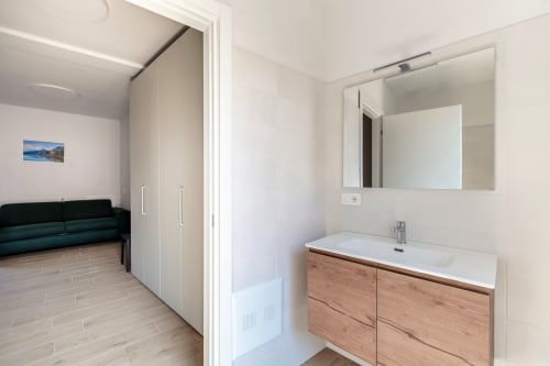 Bagno moderno presso Lago Suites Como con vanità in legno, specchio e lavabo. Camera 202 con vista sulla città.