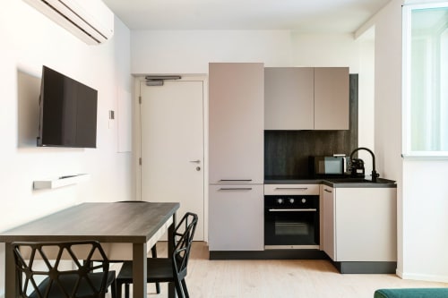 Moderna cucina studio a Lago Suites Como con tavolo da pranzo, elettrodomestici integrati e TV a parete