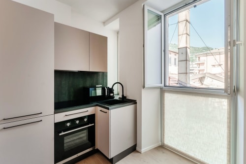 Cucina moderna nella camera 202 di Lago Suites Como con piano cottura nero, vista sulla città e arredi bianchi contemporanei