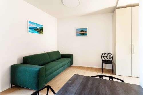 Camera moderna del Lago Suites Como con divano verde, pavimento in legno, fotografie di vedute cittadine e arredi contemporanei