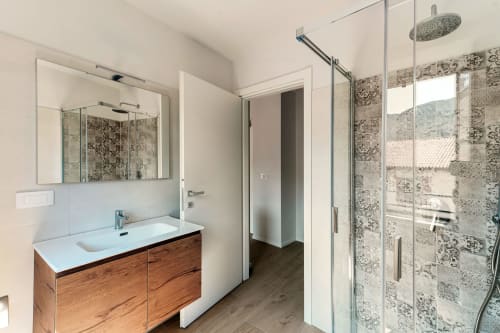Bagno moderno presso Lago Suites Como con mobile in legno, doccia in piastrelle decorative e soffione a pioggia