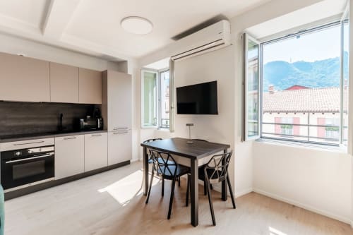 Cucina e zona pranzo moderna presso Lago Suites Como con vista montagna, TV e arredi contemporanei