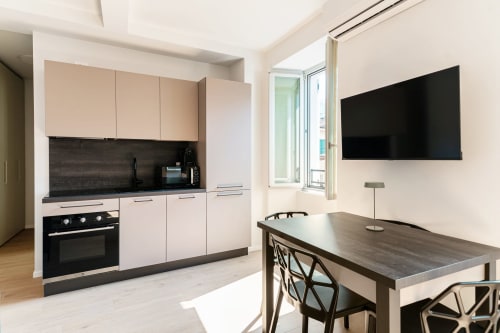 Cucina moderna e zona pranzo presso Lago Suites Como con TV a schermo piatto, piano cottura nero e vista sulla città dal balcone