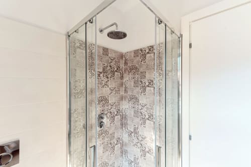 Moderna cabina doccia in vetro con pareti rivestite di piastrelle decorate presso l'hotel Lago Suites a Como, Italia