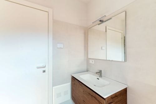 Bagno moderno presso Lago Suites Como con vanity in legno, lavabo bianco, specchiera e cabina doccia in vetro