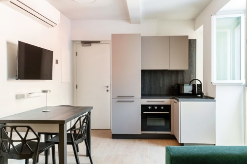 Cucina e zona pranzo moderna presso Lago Suites Como con TV a schermo piatto, mobili eleganti e vista sulla città