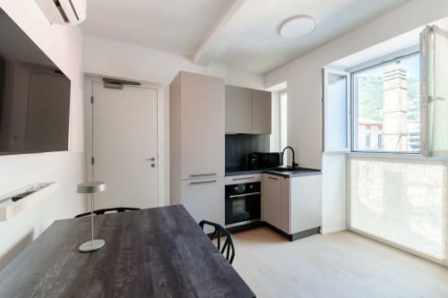 Cucina moderna presso Lago Suites Como con tavolo da pranzo scuro, elettrodomestici in acciaio inox e finestre con vista sulla città